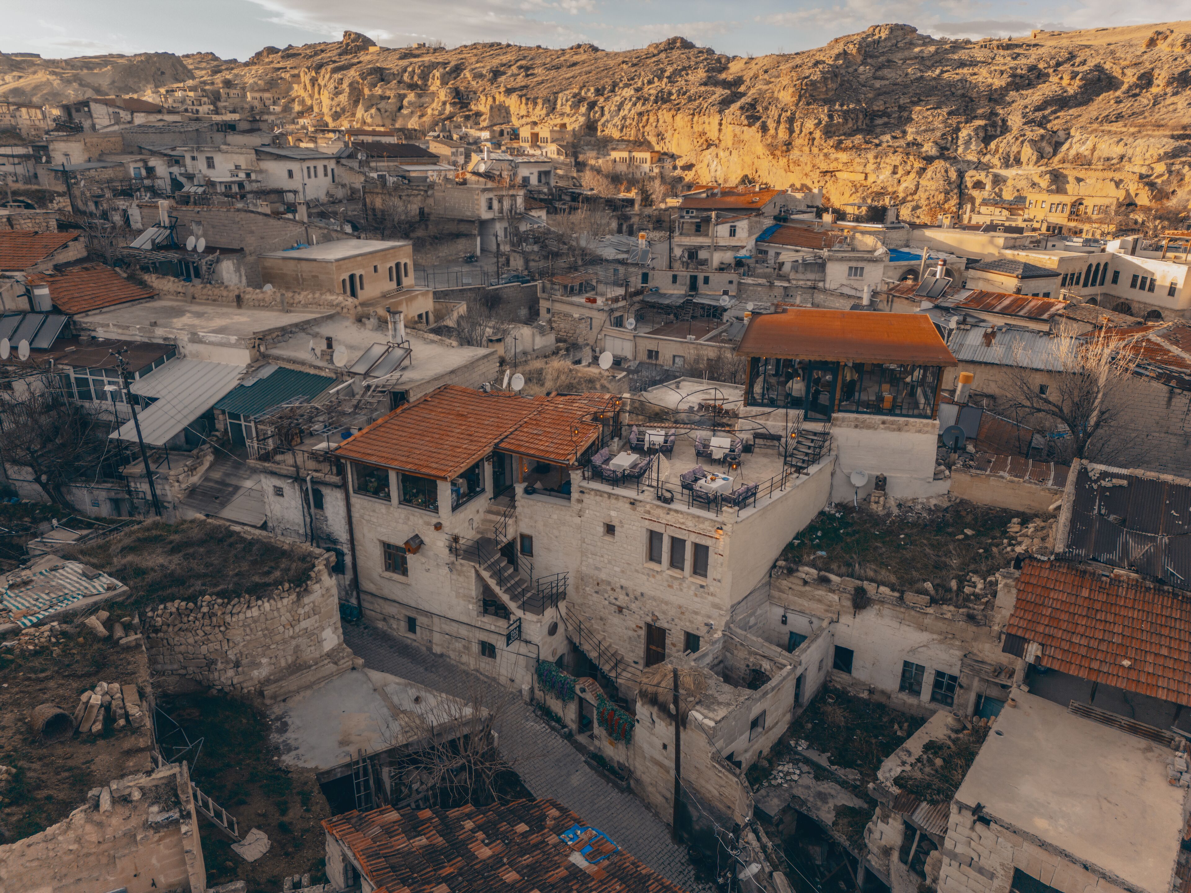 An aerial view of a densely packed urban area with buildings of varying heights and architectural styles, including some with flat roofs and others with sloped roofs.