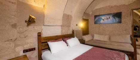 A bedroom with a wooden bed, a sofa, and a painting on the wall.