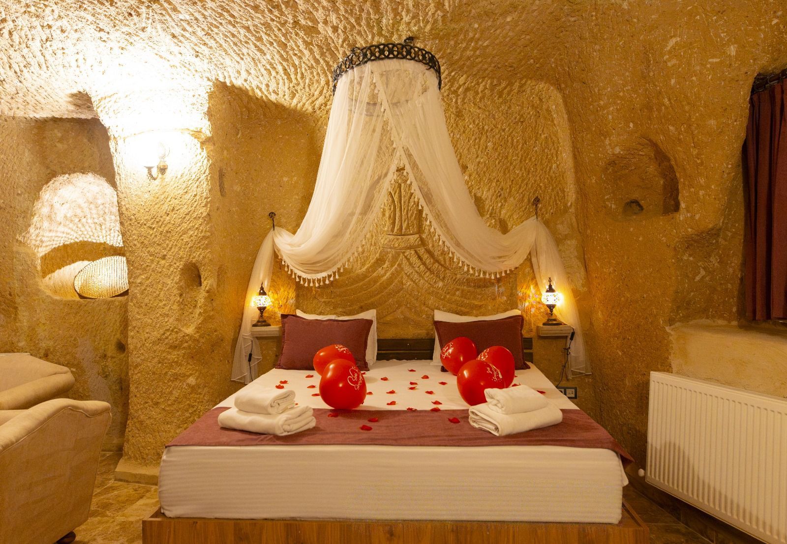 A room with a bed, two bedside tables, and a large, textured wall.