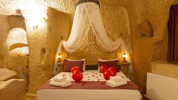 A room with a bed, two bedside tables, and a large, textured wall.