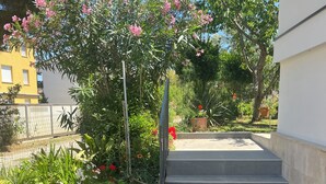 A staircase leading up to a building, surrounded by a garden with various plants and flowers. - Apartman u Volme, Medulin (Banjole)