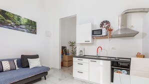 A modern kitchen with white cabinets, a microwave, and a stainless steel range hood. - Apartman u Volme, Medulin (Banjole)