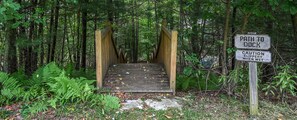 A wooden bridge leading to a community dock with a caution sign about slippery conditions when wet. - Carefree Cove by Taylor Made Deep Creek (Swanton)