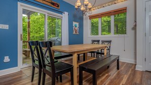 A dining area with a wooden table and chairs, a bench, and a chandelier. - Carmel Sunday by Taylor Made Deep Creek (Swanton)