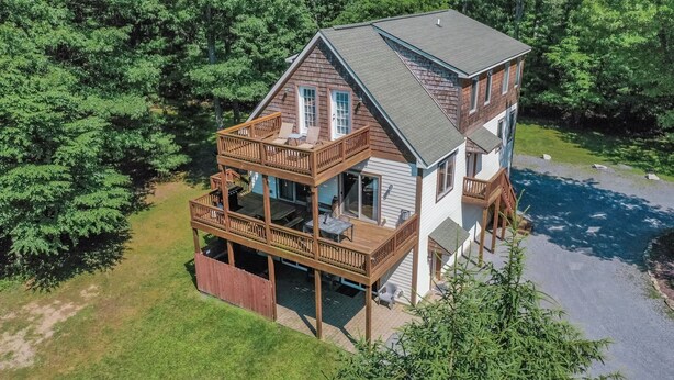A two-story cabin with a balcony, surrounded by trees. - Carmel Sunday by Taylor Made Deep Creek (Swanton)