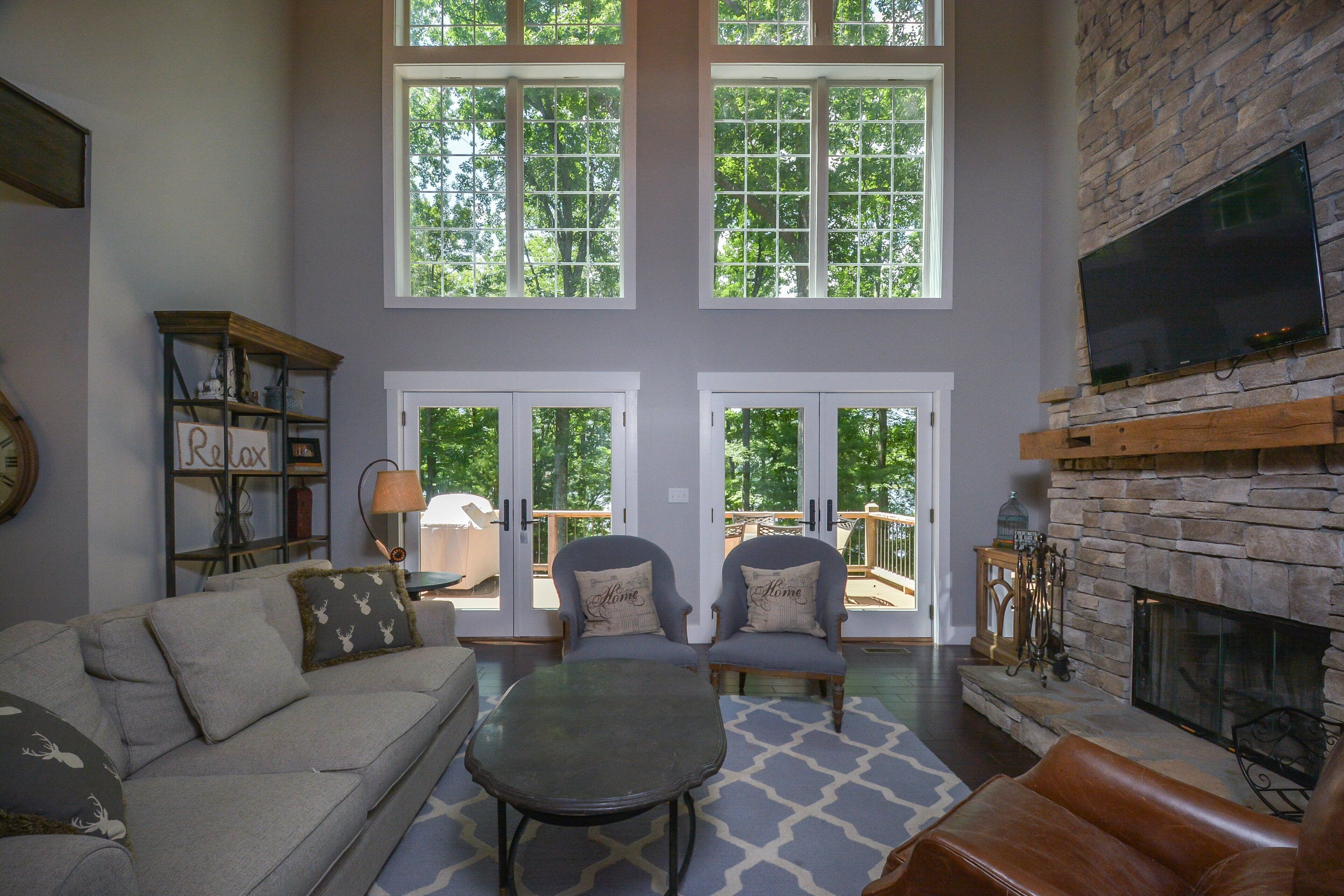 A spacious living room with a stone fireplace, large windows, and a cozy seating area.