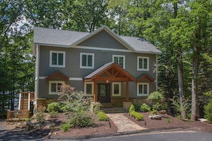 A two-story house with a stone foundation, a front porch, and a landscaped garden.