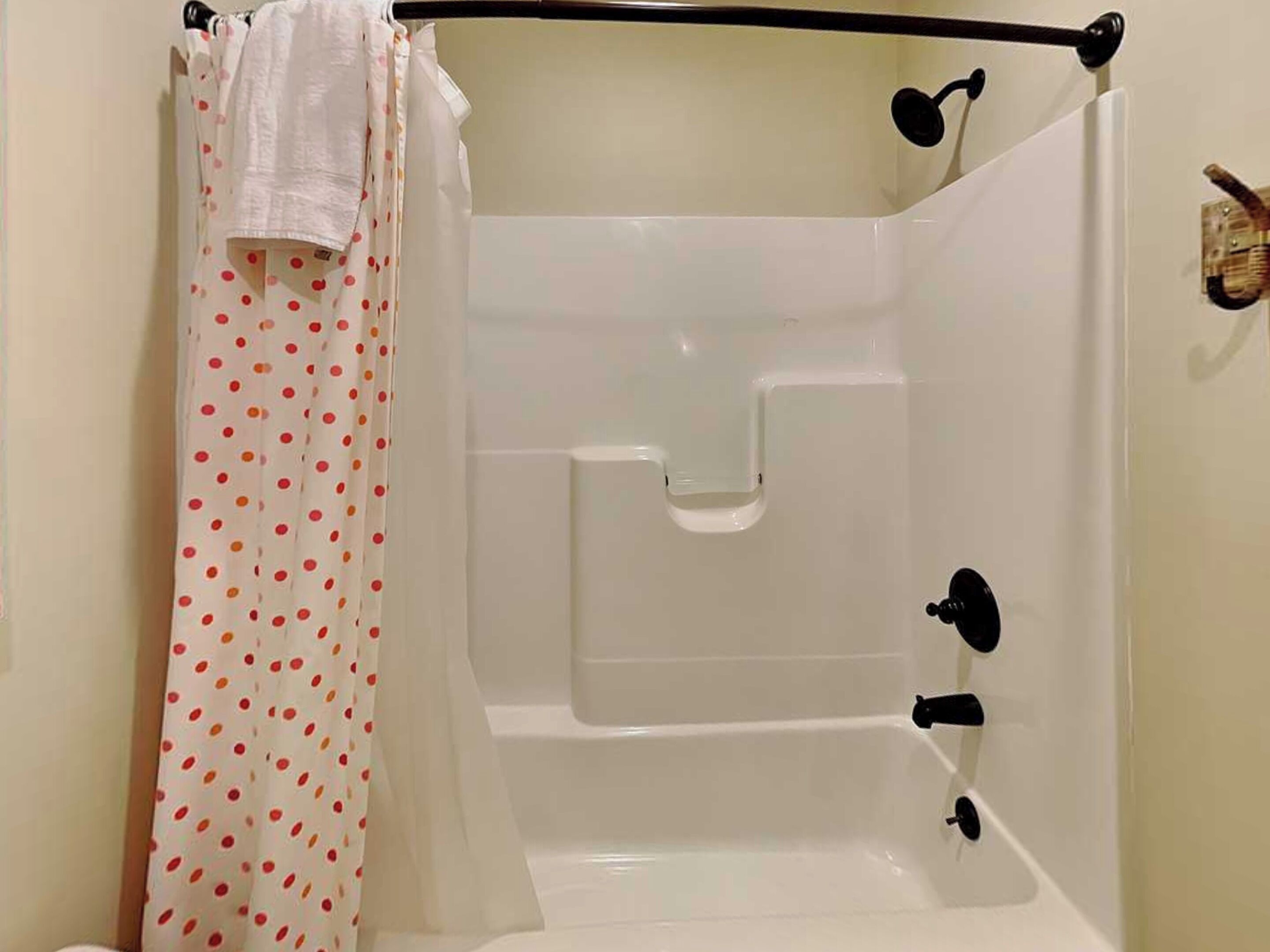 A white bathtub with a shower curtain, a faucet, and a handheld showerhead.