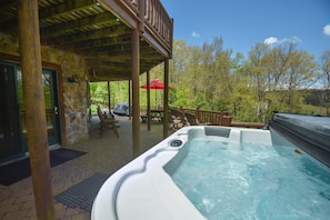 Relax in a hot tub on a deck surrounded by comfortable outdoor furniture.