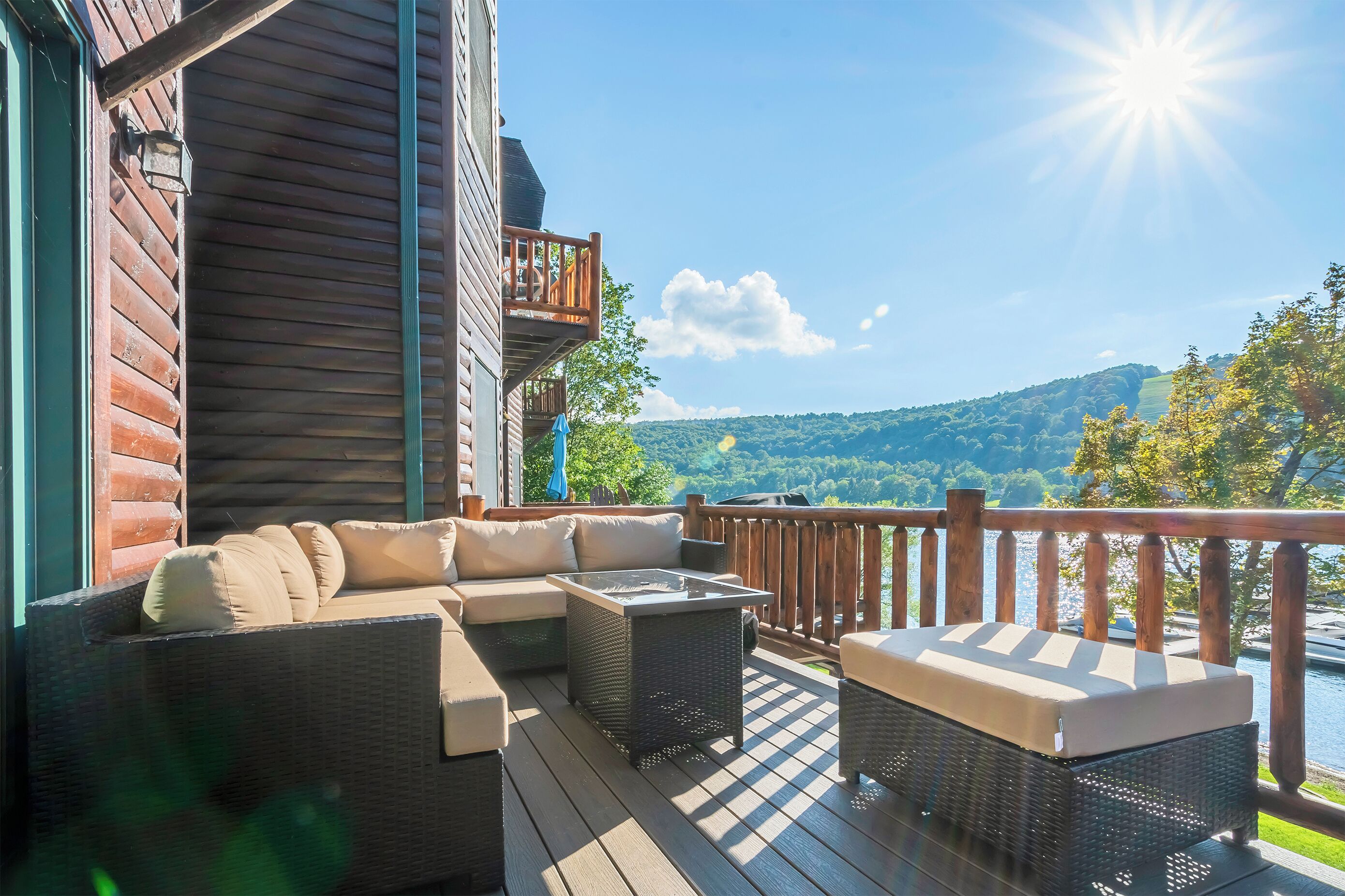 Terraza de madera con sofá y una mesa, con vistas a un paisaje pintoresco.