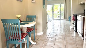 A dining area with a round table and chairs, a ceiling fan, and a view to a balcony with curtains. - Paradise Stay Studio-Beaches-Relax-Nature-Free Parking (Providenciales)