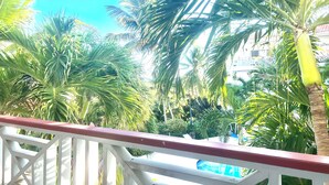A balcony with a view of palm trees and a building in the background. - Paradise Stay Studio-Beaches-Relax-Nature-Free Parking (Providenciales)