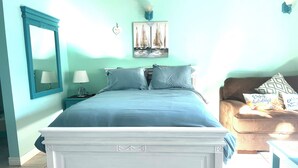 A bedroom with a bed, a nightstand, a lamp, a mirror, a wall art, and a sofa. - Paradise Stay Studio-Beaches-Relax-Nature-Free Parking (Providenciales)