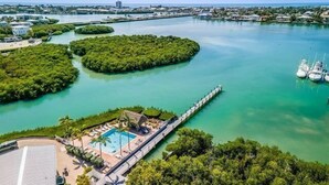 An aerial view of a coastal area with a marina, a swimming pool, and lush greenery.