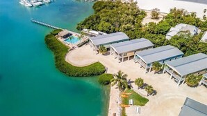 An aerial view of a coastal property with a marina, a swimming pool, and several buildings.