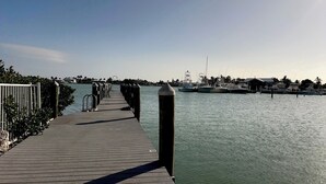 A wooden pier extending into calm water with boats docked in the background. - Sunset Pointe at Vaca Cove4 Bed 3 Baths, Saltwater Pool, Jacuzzi, Ocean View with Dock (Marathon)