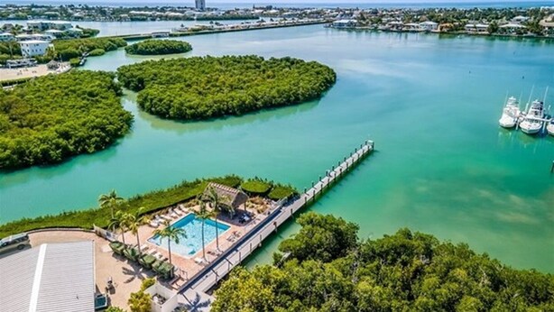 An aerial view of a coastal area with a marina, a swimming pool, and lush greenery. - Sunset Pointe at Vaca Cove4 Bed 3 Baths, Saltwater Pool, Jacuzzi, Ocean View with Dock (Marathon)