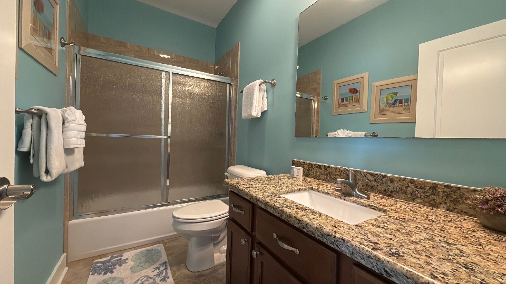 A bathroom with a shower, toilet, sink, and cabinets.