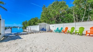 A beach with a pool, colorful Adirondack chairs, and a covered area. - Sunset Pointe at Vaca Cove4 Bed 3 Baths, Saltwater Pool, Jacuzzi, Ocean View with Dock (Marathon)