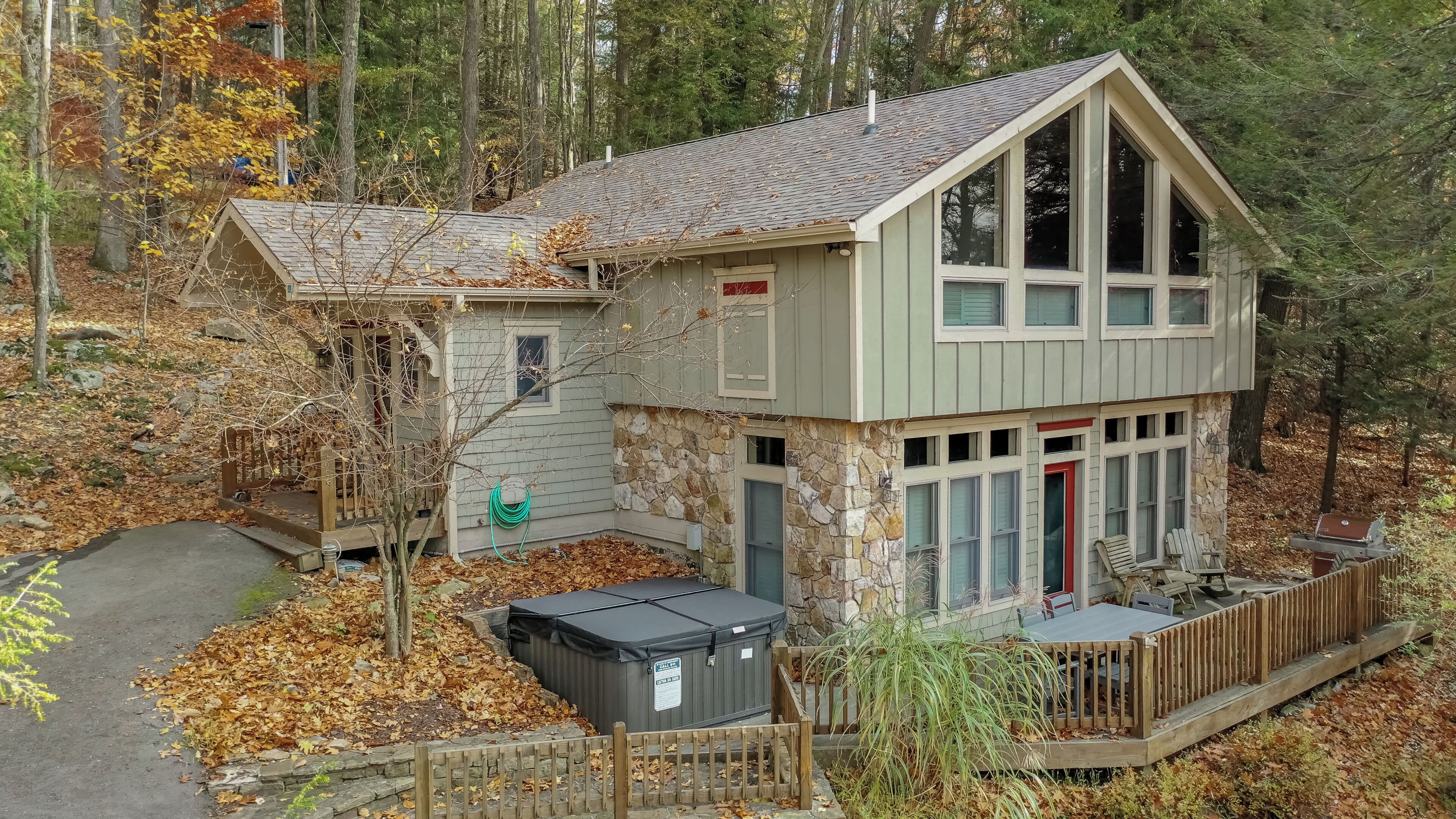 A cabin with a stone exterior, a wooden deck, and a covered outdoor seating area.
