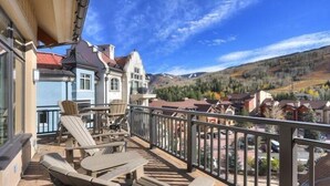 A balcony with outdoor seating, overlooking a mountainous landscape with houses. - Luxury Mountain-Side Penthouse with Stunning Views! by RedAwning (Vail)