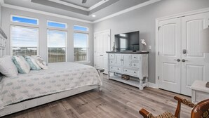 A bedroom with a bed, a dresser, a TV, and a ceiling fan.