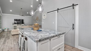 A kitchen with a marble countertop, white cabinets, and a sliding barn door.