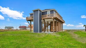 A two-story house with a balcony, a covered porch, and a grassy yard.