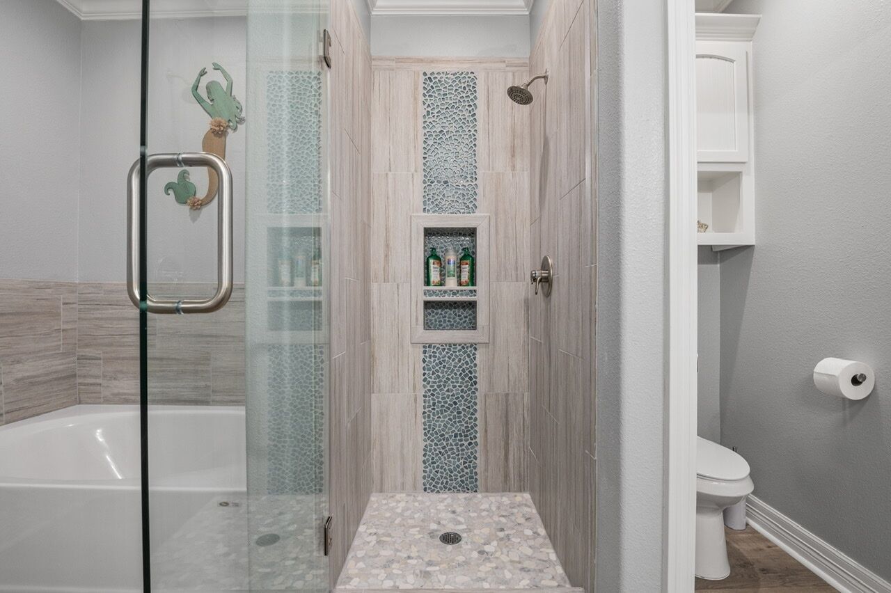 A modern bathroom with a glass-enclosed shower, a white bathtub, and a toilet.