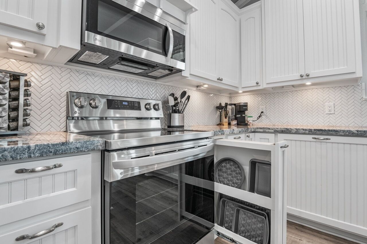 Et moderne køkken med rustfrie hårde hvide skabe og et backsplash i fiskebensmønster.