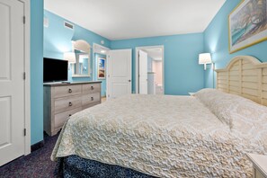 A bedroom with a large bed, a dresser, a television, and a door leading to another room. - Avista Resort 1503 1 Bedroom Condo by RedAwning (North Myrtle Beach)