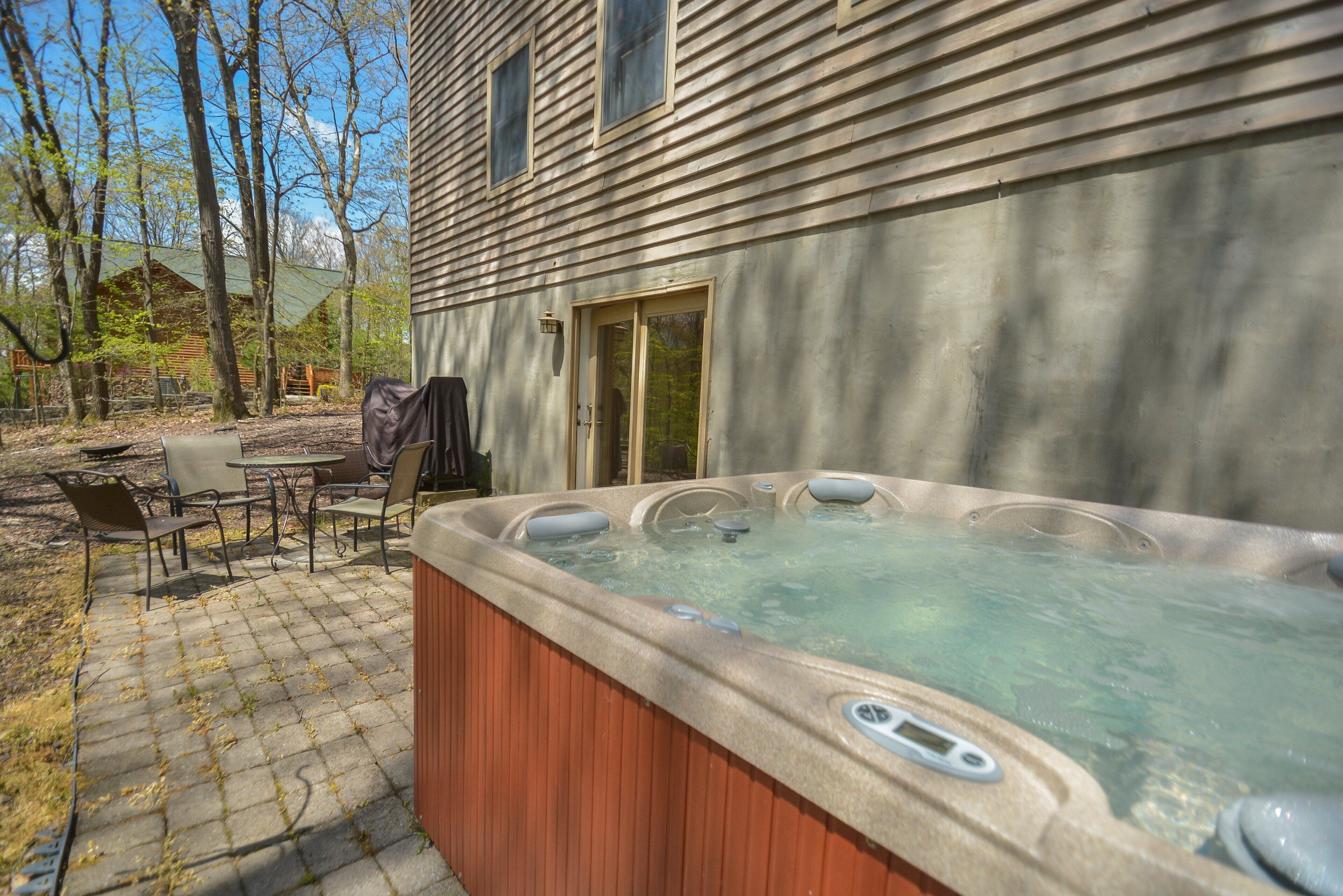 Een hottub in een achtertuin met een patio tafel en stoelen.