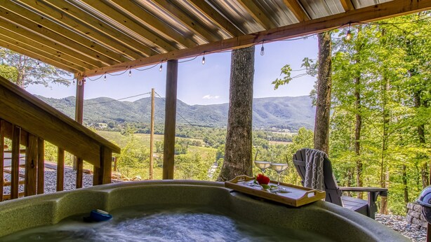 Un jacuzzi con cubierta de madera y vista a las montañas.