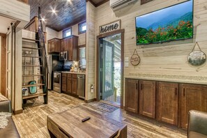 A modern kitchen with wooden cabinets, a stainless steel refrigerator, and a large window overlooking a scenic landscape.