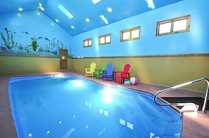 An indoor swimming pool with a mural of underwater scenery, a wooden door, and colorful Adirondack chairs along the wall. - Celebration at Deep Creek by Taylor Made Deep Creek (Oakland)