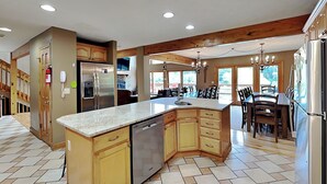 A spacious kitchen with a large island, wooden cabinets, and a built-in dishwasher. - Celebration at Deep Creek by Taylor Made Deep Creek (Oakland)