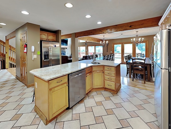 A spacious kitchen with a large island, wooden cabinets, and a built-in dishwasher. - Celebration at Deep Creek by Taylor Made Deep Creek (Oakland)
