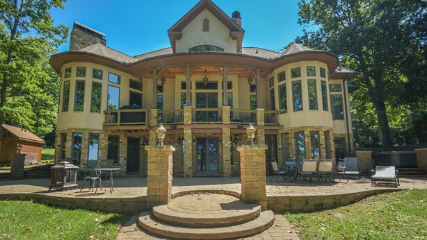 A large, two-story house with a central courtyard, stone columns, and a covered patio area. - Champagne Taste by Taylor Made Deep Creek (Oakland)