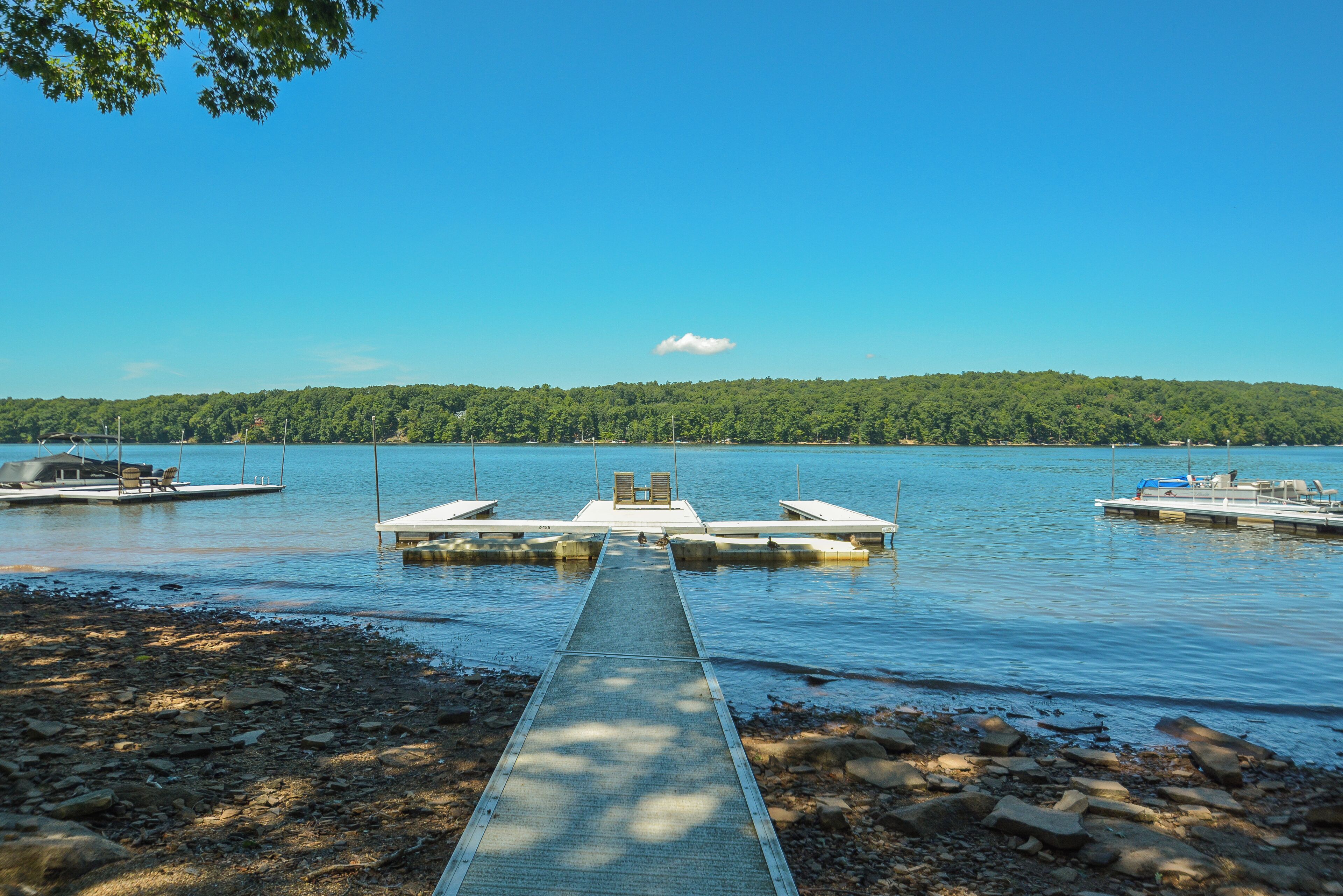 A dock extending into calm water with boats moored at the end.