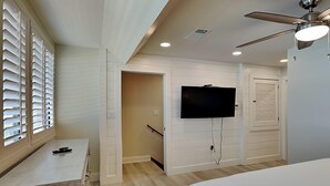 A bedroom with a bed, a desk, a television mounted on the wall, and a ceiling fan. - Aegean #332 - Gulf-Front Views, Relaxing Amenities (Destin)
