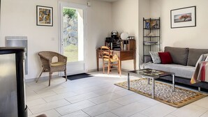 A modern living room with a sofa, a coffee table, a wicker chair, a bookshelf, and a radiator. - VILLA LA COTINIERE (Saint-Pierre-d'Oléron)