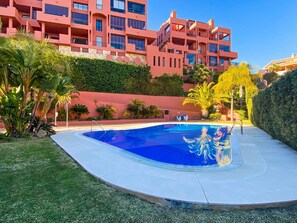 Uma piscina rodeada por um relvado bem cuidado e plantas tropicais.