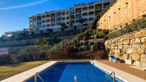 Una piscina con una pared de piedra y un edificio al fondo.