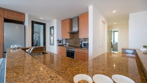 Una cocina moderna con encimeras de granito, electrodomésticos de acero inoxidable y armarios de madera.