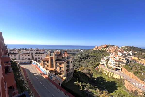 Uma vila costeira com edifícios ao longo de uma estrada sinuosa, com vista para o mar.