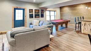 A spacious living area with a pool table, a sofa, and a bar area. - Cj's Mountain Lodge by Taylor Made Deep Creek (McHenry)