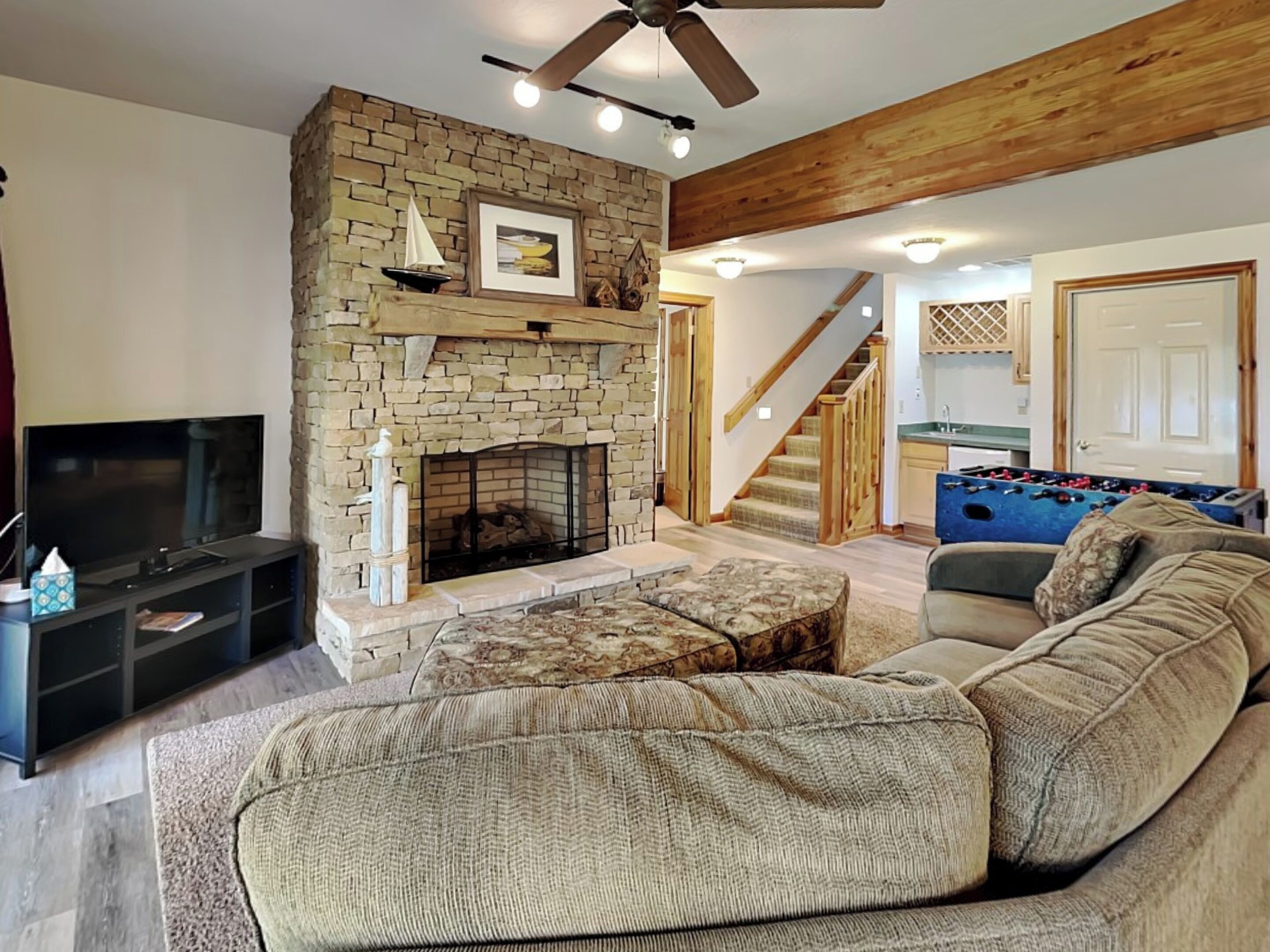 A living room with a stone fireplace, a television, and a sofa.