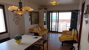 A dining area with a table and chairs, a sofa, and a balcony with a table and chairs.