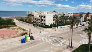 A coastal building with multiple balconies, a parking area with bollards, and a view of the beach and sea. - Las Olas  4º Solo Familias! (Xeraco Playa)