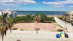 A coastal view with a beach, palm trees, and a parking area with trash bins. - Las Olas  4º Solo Familias! (Xeraco Playa)